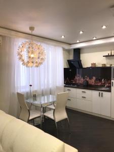 a kitchen with a table and chairs and a chandelier at Art Apartments in Volgograd