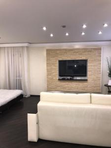 a living room with a white couch and a flat screen tv at Art Apartments in Volgograd