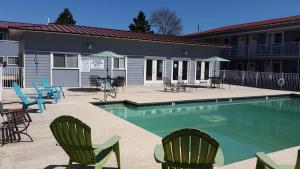 a swimming pool with chairs and tables and a building at Beach Comber at Oak Shores in Biloxi