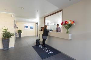 a woman standing at a reception desk in a store at Quest Ponsonby Serviced Apartments in Auckland