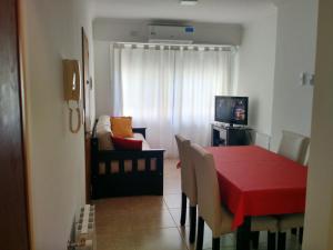 a dining room with a red table and a couch at Check in Angeles Bahía in Bahía Blanca