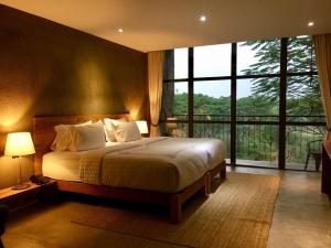 a bedroom with a bed and a large window at Inchantreedoopool in Kanchanaburi City +37 photos