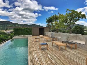 a swimming pool with benches on a wooden deck at Inchantreedoopool in Kanchanaburi City
