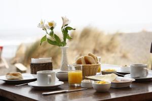 a table with breakfast foods and a glass of orange juice at Pichilemu Surf Hostal in Pichilemu