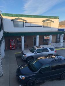 twee auto's geparkeerd op een parkeerplaats voor een winkel bij Kootenay Country Inn in Cranbrook