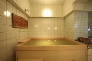 y baño con bañera grande y azulejos blancos. en Hotel New Station, en Matsumoto