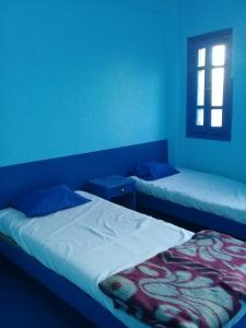 two beds in a room with blue walls and a window at Oasis hotel in Luxor