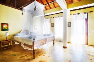 sypialnia z łóżkiem z moskitierą w obiekcie Villa Lucky Star w Tangalli