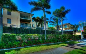 a building with palm trees and a fence at Bila Vista Kirra Beachside Apartments in Gold Coast