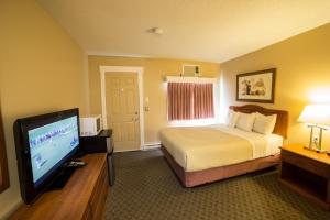 a hotel room with a bed and a flat screen tv at Midway Motel in Brandon