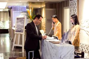 Zwei Männer und eine Frau stehen an einem Tisch im Laden. in der Unterkunft Platinum Adisucipto Hotel & Conference Center in Yogyakarta