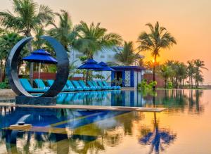 a pool with chairs and umbrellas in front of a resort at Azaya Beach Resort Goa in Benaulim