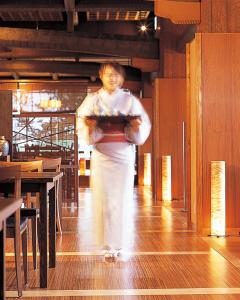 a woman is holding a tray of food at Hotel Kinparo in Toyooka