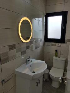 a bathroom with a sink and a toilet and a mirror at Kings Avenue - Natalia's Apt in Paphos