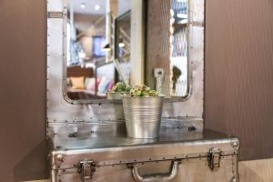 a mirror with two potted plants on a metal trunk at arte Hotel Wien Stadthalle in Vienna