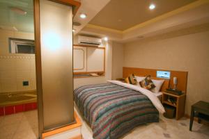 a small bedroom with a bed and a bathroom at Hotel Celavie Osakajokitazume (Adult only) in Osaka