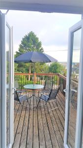 a table and chairs on a deck with an umbrella at Swindon Old Town Duplex - EnterCloud9SA in Swindon