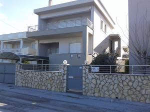 a large white house with a stone wall at Vrachati Sea Front House in Káto Ássos