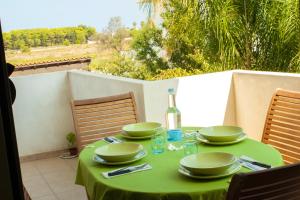 einem grünen Tisch mit Tellern und einer Flasche Wein in der Unterkunft Con PISCINA e GARAGE a 300 m da spiaggia e centro in Torre dell'Orso