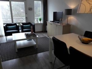 a living room with a table and chairs and a television at Hollumerstrand in Hollum