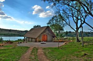 une grange avec une porte rouge dans un champ dans l'établissement Cradle Moon Lakeside Game Lodge, à Muldersdrift