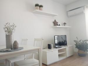 バレンシアにあるTranvia a la Playa Malvarrosaの白い部屋で、デスク、テレビ、テーブルが備わります。