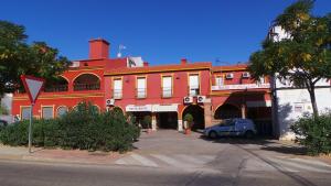 a red building with a car parked in front of it at Hostal El Chiringuito in Valverde de Leganés