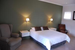 1 dormitorio con 1 cama blanca y 1 silla en Longacre Olive & Vineyard Estate, en Langebaan