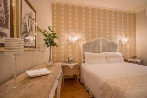 een slaapkamer met een wit bed en een houten bureau bij Domus Verona - Incantevole residenza difronte a casa Giulietta in Verona