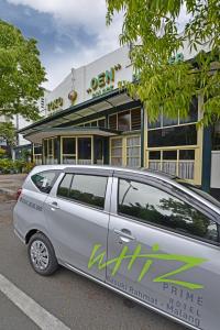 a van parked in a parking lot in front of a building at Whiz Prime Hotel Basuki Rahmat Malang in Malang