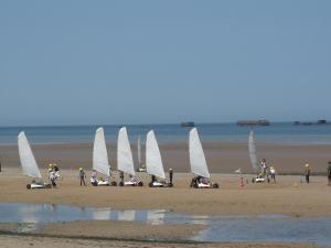 a group of people on a beach with sailboats at la glycine in Asnelles