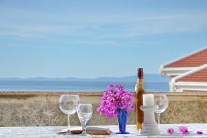 a table with glasses and a bottle of wine and flowers at Apartments Summersong in Novalja
