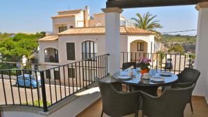 a balcony with a table and chairs and a house at Apartamentos Casa María in Cala Figuera