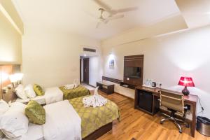 a hotel room with two beds and a desk at Diamond Hotel in Varanasi