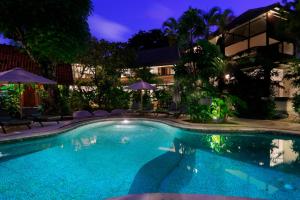 a swimming pool in front of a hotel at night at Pearl Boutique Hotel Adult only in Legian