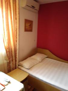 フォクシャニにあるPensiunea SENA Focsaniの赤い壁の小さな客室で、ベッド1台が備わります。