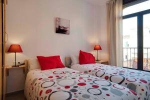 1 dormitorio con 2 camas con almohadas rojas y ventana en Angosta del Carmen, en Málaga