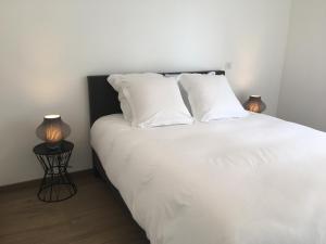 a white bed with white pillows and two lamps at Carpe Diem in Annecy