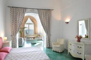 a bedroom with a bed and a chair and windows at Villa Rosa in Positano