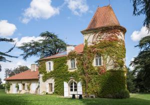 une maison recouverte de lierre avec une tour dans l'établissement Château Marteret, à Vic-Fezensac