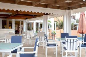 a patio with white tables and chairs and an umbrella at Archotel in Dakar