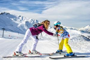 uma mulher e uma criança em esquis na neve em Résidence Goélia - Le Rond Point des Pistes em Saint-François-Longchamp