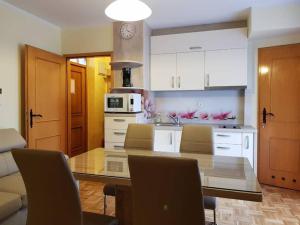 a kitchen with a dining table with chairs and a kitchen with white cabinets at TULPIKA 13 in Moravske-Toplice