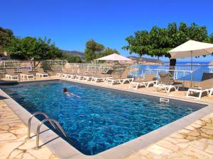 a pool with chairs and a person swimming in it at Résidence Marine de Palumbare in LʼÎle-Rousse