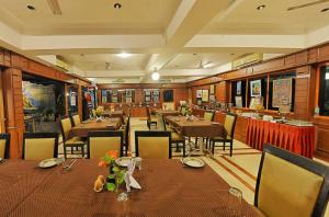een restaurant met houten tafels en stoelen en een tafeltennistafel bij Hotel Mahabs in Mahabalipuram