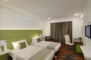 a hotel room with two beds and a desk at Lemon Tree Hotel, Banjara Hills, Hyderabad in Hyderabad