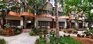 a building with a courtyard with trees and plants at Hotel Mahabs in Mahabalipuram