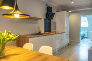 a kitchen with white cabinets and a wooden table at Apartamenty Pod Gubałówką in Zakopane