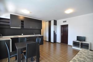 a kitchen with black cabinets and a table with chairs at Guest House ASK in Primorsko
