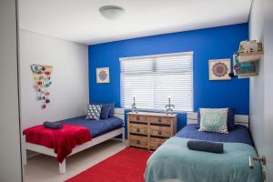 ein Schlafzimmer mit zwei Betten und einer blauen Wand in der Unterkunft Turmalin Cottage Unit 1 in Swakopmund
